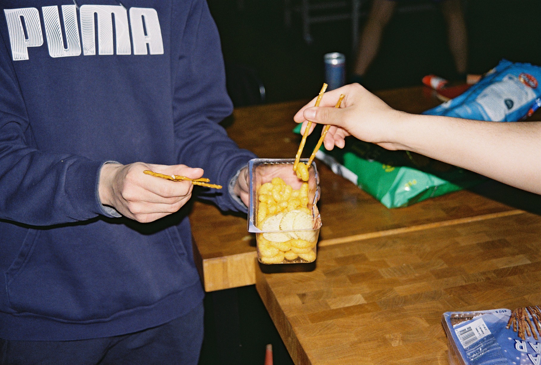 Two people eating snacks from a plastic container